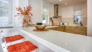 A modern kitchen with white countertops, a large island, and wooden cabinets. - Pool Villa Ora in Nature (Marcana)