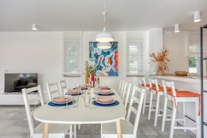 Un comedor con una mesa blanca, sillas y un cuadro en la pared.