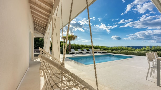 A pool area with a hammock, lounge chairs, and a view of the landscape. - Pool Villa Ora in Nature (Marcana)