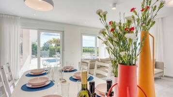 Uma sala de jantar com uma mesa posta para quatro pessoas, uma garrafa de vinho e um vaso com flores.