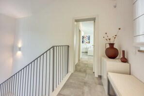 A hallway with a staircase, a white wall, and a door leading to another room. - Pool Villa Ora in Nature (Marcana)