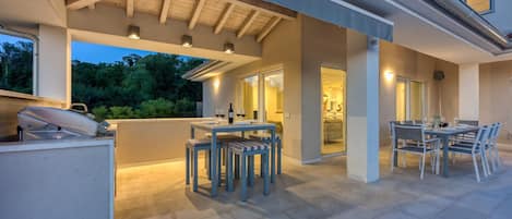 An outdoor patio area with a grill, seating, and a view of the interior.