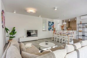 Una sala de estar moderna con sofá, mesa de comedor y televisor.