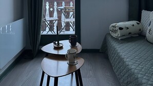 A small, cozy room with a bed, a table with a cup, and a view of a balcony with outdoor furniture. - Studio cabin at the foot of the slopes - Valfréjus (Valfréjus)