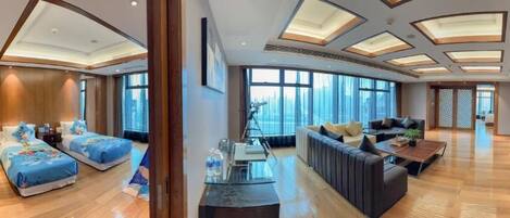 A modern hotel room with two beds, a sofa, a coffee table, and large windows offering a city view.