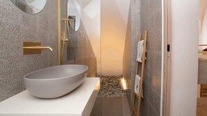 A modern bathroom with a large oval sink, a shower with a golden showerhead, and a mirror with a unique shape. - Spring - The Fab Stay (Ostuni)