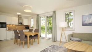 A modern kitchen with a dining area, a sofa, and a lamp. - Beachfront apartment with terrace - Rex Rugia House 17 Apartment 01 - Beach Resort (Mönchgut)