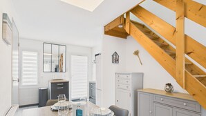Un coin repas avec une table en bois dressée pour deux personnes, un miroir et un escalier.