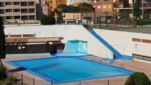 Ein Swimmingpool mit blauer Veranda, umgeben von einem Zaun, und eine Treppe, die zu einem Gebäude führt.