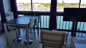 Ein Essbereich mit Tisch und Stühlen, einem Fernseher und Blick auf eine Marina mit Booten.