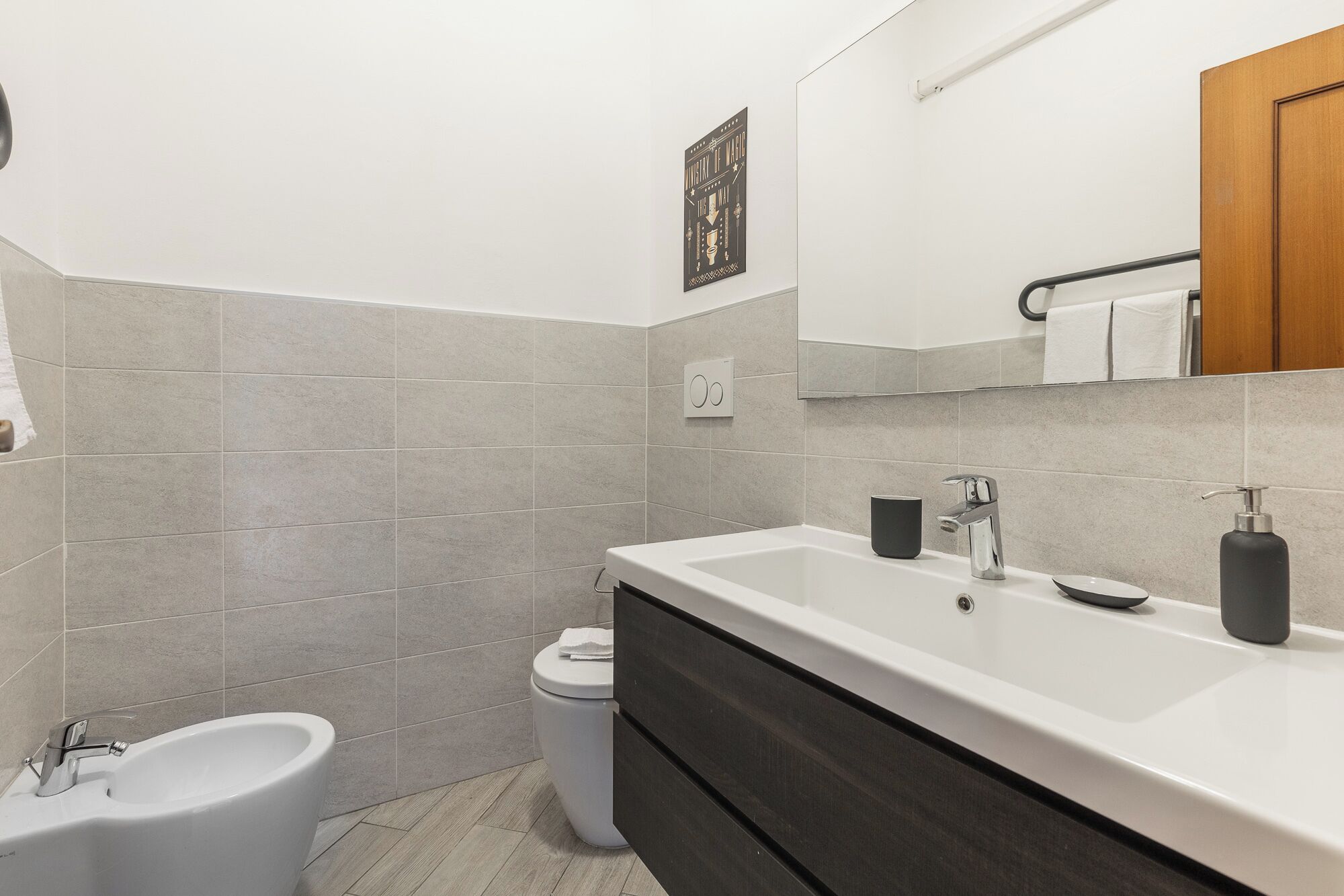 Een moderne badkamer met een witte wastafel, een donker houten wastafelmeubel en een toilet.