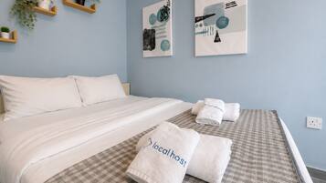 A hotel room with a bed, two towels with 'localhost' branding, a checkered bedspread, and wall art.