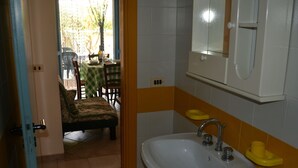 Un baño con lavamanos, espejo y jabonera amarilla.