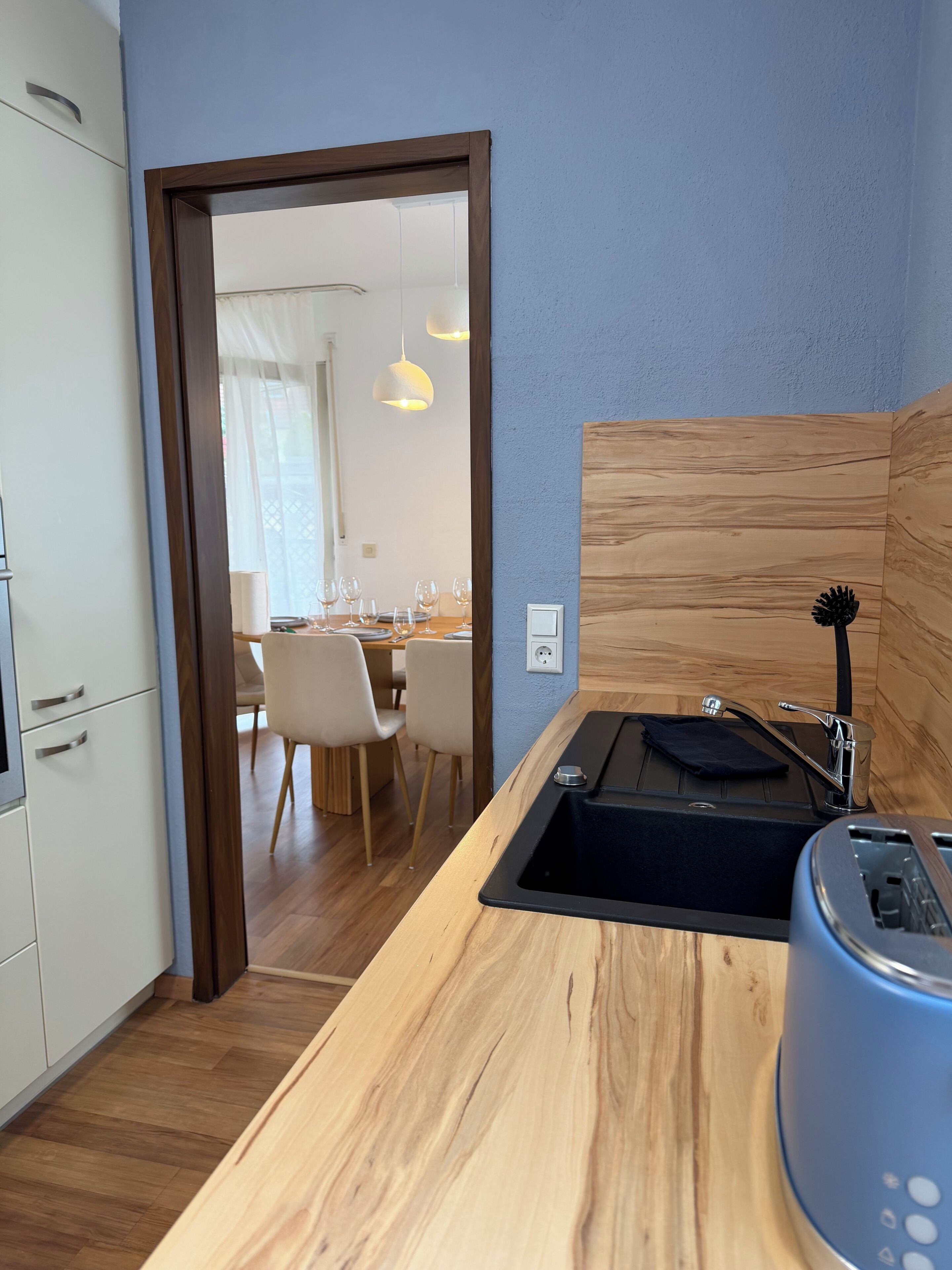 Eine moderne Küche mit einer Holzausziehtischplatte, einem Spülbecken und einem blauen Toaster.