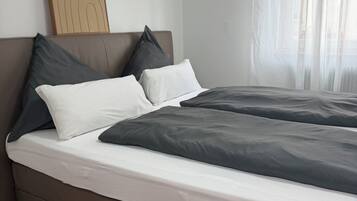 Ein modernes Schlafzimmer mit einem großen Bett, einem Kopfteil mit dekorativer Zarge und Holzboden.