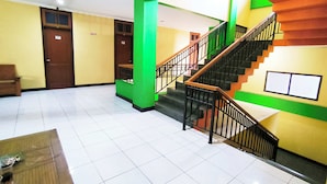 Eine Hotelhalle mit Treppe, einer Holzbank und einem Fliesenboden.