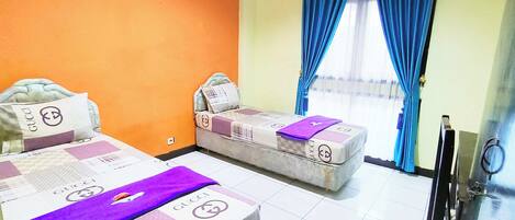A hotel room with two beds, each with a Gucci blanket, a small sofa, and a TV.
