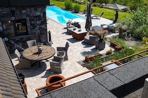 Una terrazza a bordo piscina con mobili da esterno, un muro in pietra e vista sulla piscina.