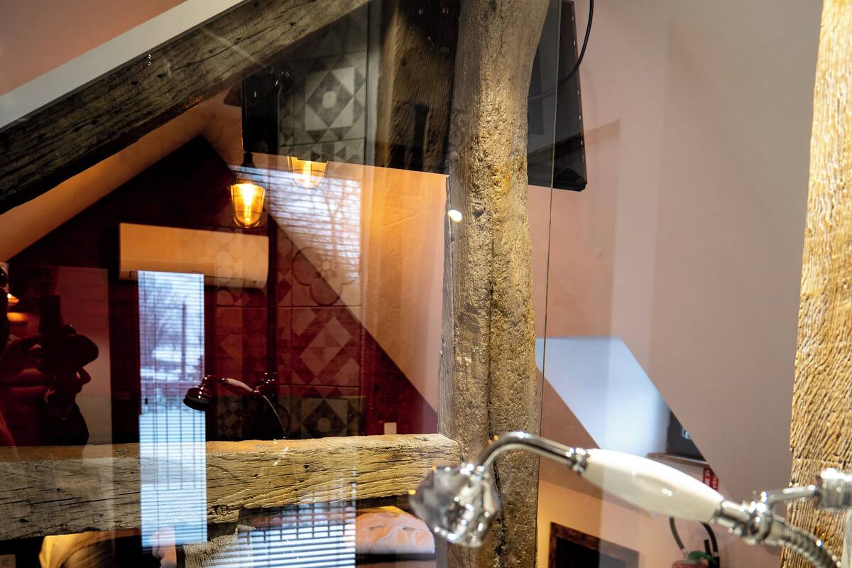 A modern interior with a wooden staircase, a glass partition, and a visible shower area.