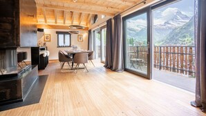 A modern kitchen with a large island, wooden ceiling, and a view of a mountain landscape. - Akelei Penthouse by HomeFlow Zermatt (Zermatt)