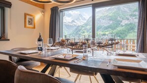 A dining table set with plates, glasses, and a bottle, overlooking a mountainous landscape. - Akelei Penthouse by HomeFlow Zermatt (Zermatt)