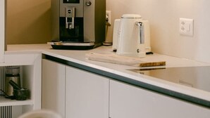 Une petite cuisine équipée d’une machine à café, d’un distributeur d’eau et d’un grille-pain.