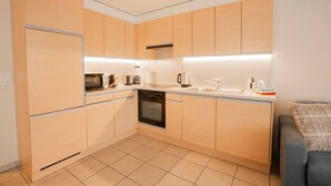 Une cuisine compacte avec des meubles de couleur bois clair, un four encastré, un four à micro-ondes et un évier.