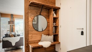 A cozy room with a wooden accent wall, a round mirror, a white fluffy throw, and a small shelf with decorative items. - Zenith B by HomeFlow Zermatt (Zermatt)