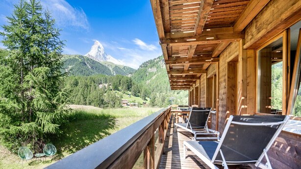 A wooden deck with lounge chairs overlooking a mountainous landscape. - Galileo by HomeFlow Zermatt (Zermatt)