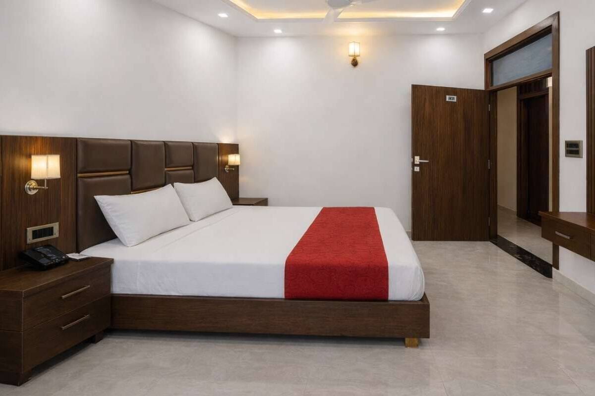 Une chambre d’hôtel avec un grand lit, une tête de lit en bois, des lampes de chevet, une télévision et une armoire.