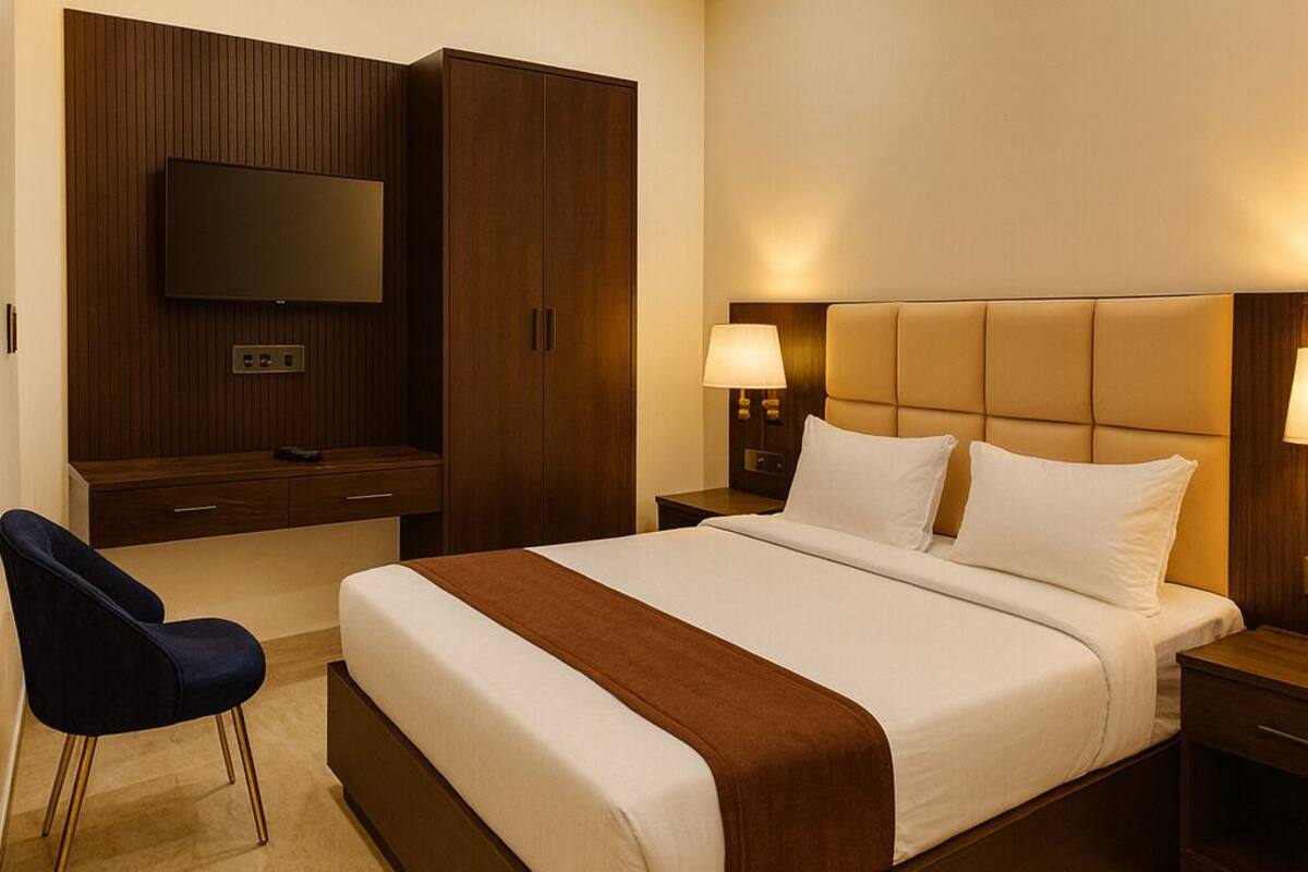 Une chambre d’hôtel moderne dotée d’un grand lit, d’un téléviseur à écran plat fixé au mur, d’un bureau avec une chaise et d’une table de chevet avec des lampes.