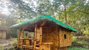 A bamboo hut with a thatched roof, surrounded by greenery. - El Bosque Resort (Coron)