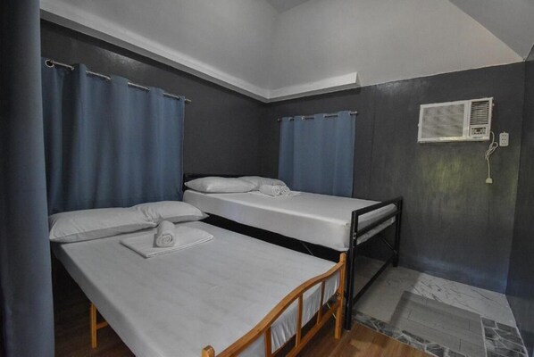 Een kamer met twee eenpersoonsbedden, een klein tafeltje en een wandairconditioning.