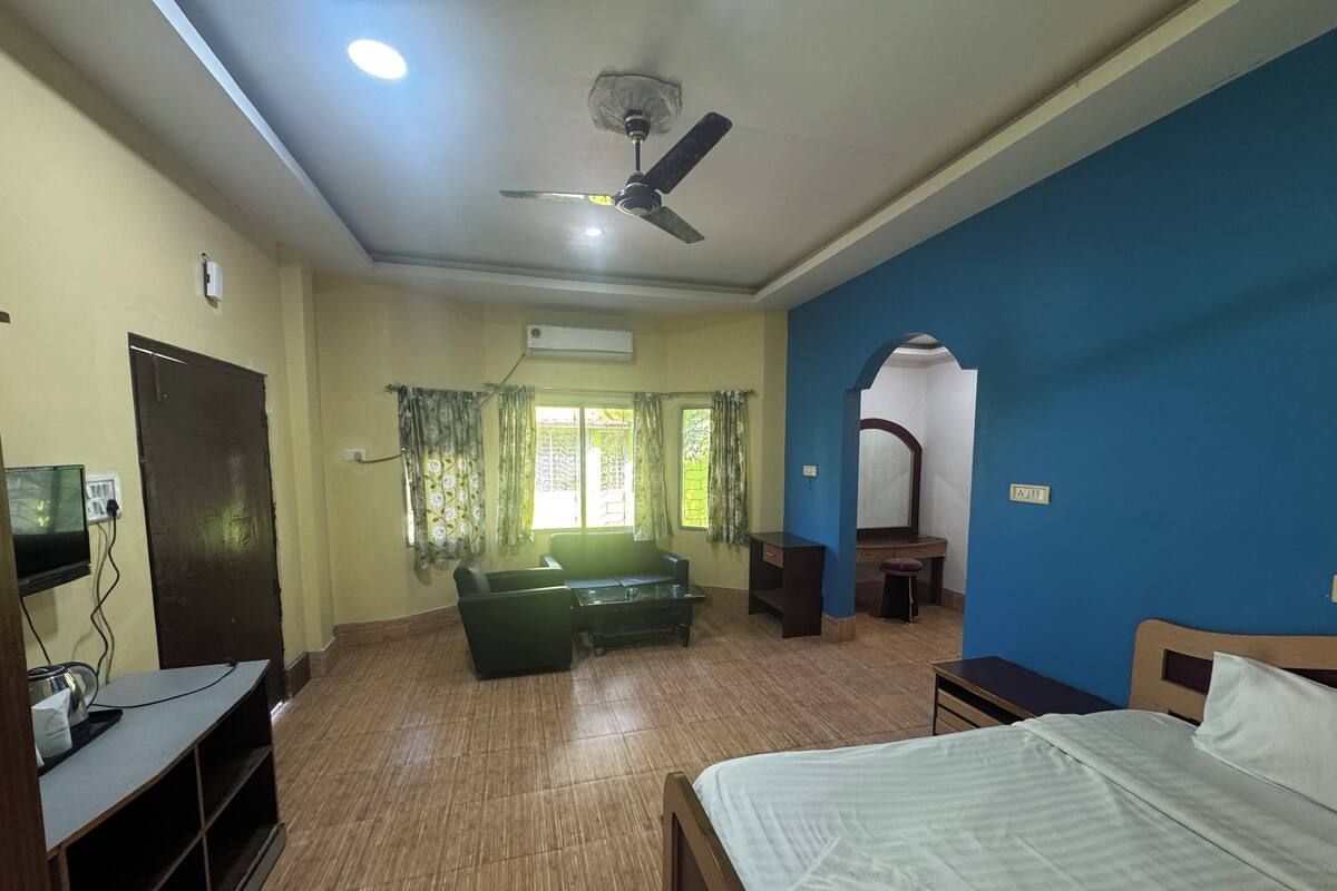 A room with a bed, a desk, a chair, a television, and a ceiling fan.