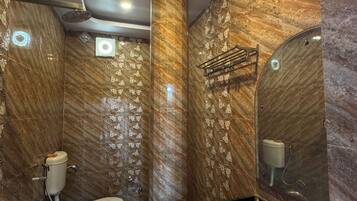 A modern bathroom with marble walls, a toilet, a sink, and a green trash bin.