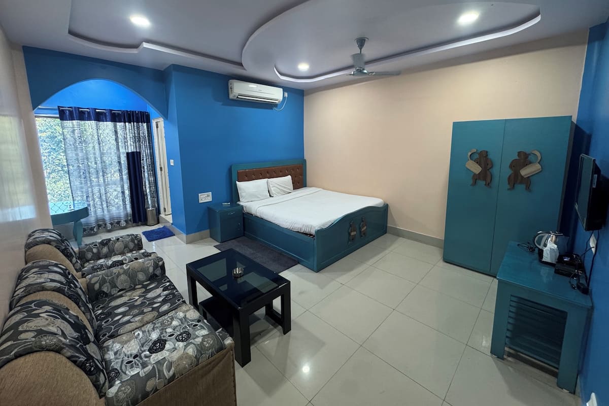A hotel room with a bed, a sofa, a coffee table, a TV, and a wardrobe.