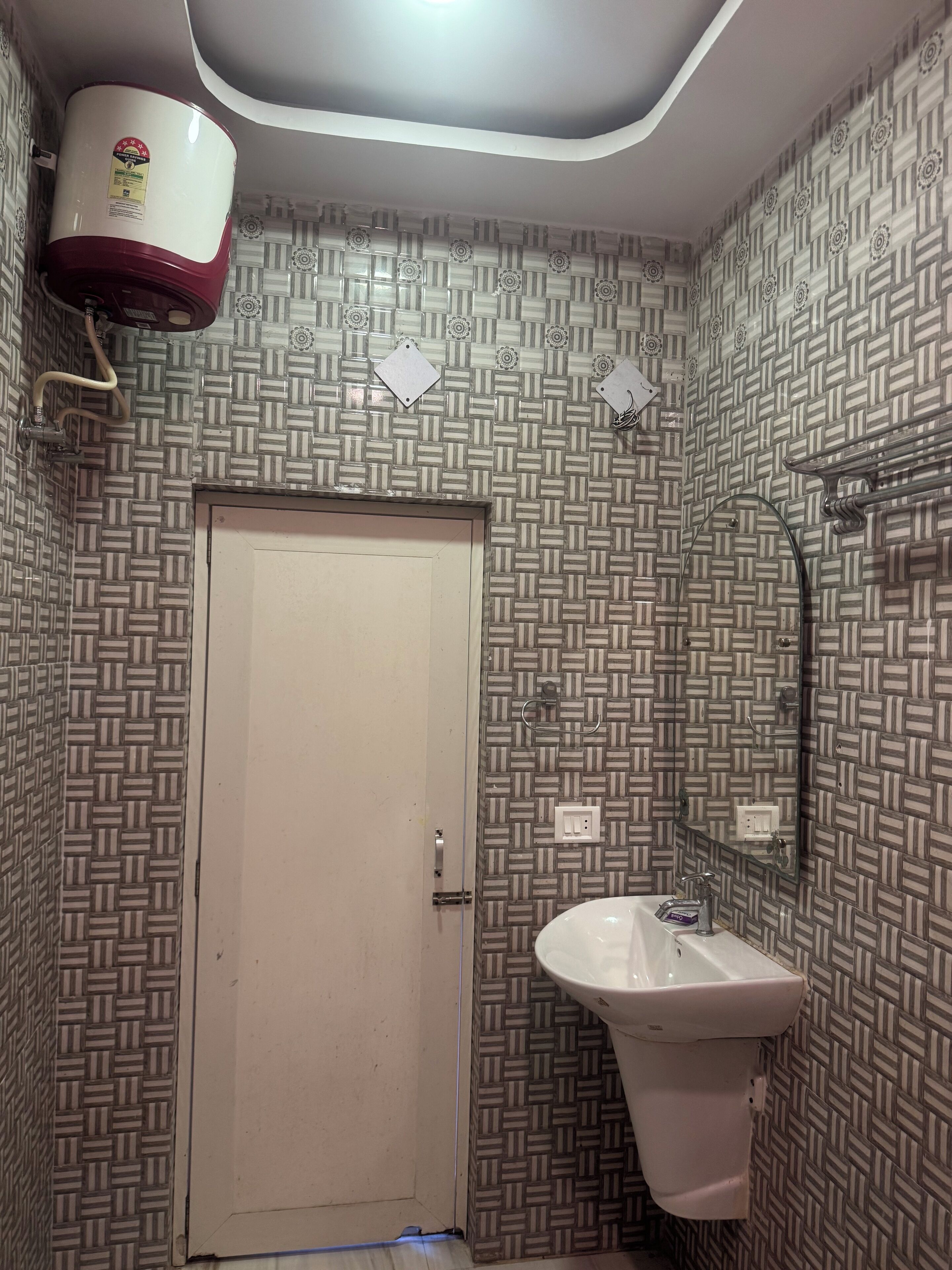 A bathroom with patterned tile walls, a white sink, and a door.