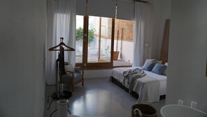 Ein Schlafzimmer mit Bett, Stuhl, einer Hängeleuchte und Blick ins Freie.