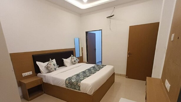 A neatly arranged bedroom with a bed, bedside table, and a small desk. - Hotel JMM Mount View (Udaipur)