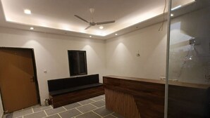 A room with a ceiling fan, a built-in bench, a radiator, and a glass partition. - Hotel JMM Mount View (Udaipur)