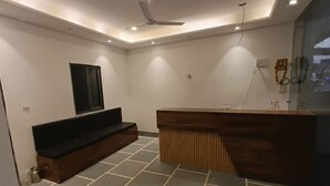 A modern reception area with a wooden counter, a flat-screen TV mounted on the wall, and a ceiling fan. - Hotel JMM Mount View (Udaipur)