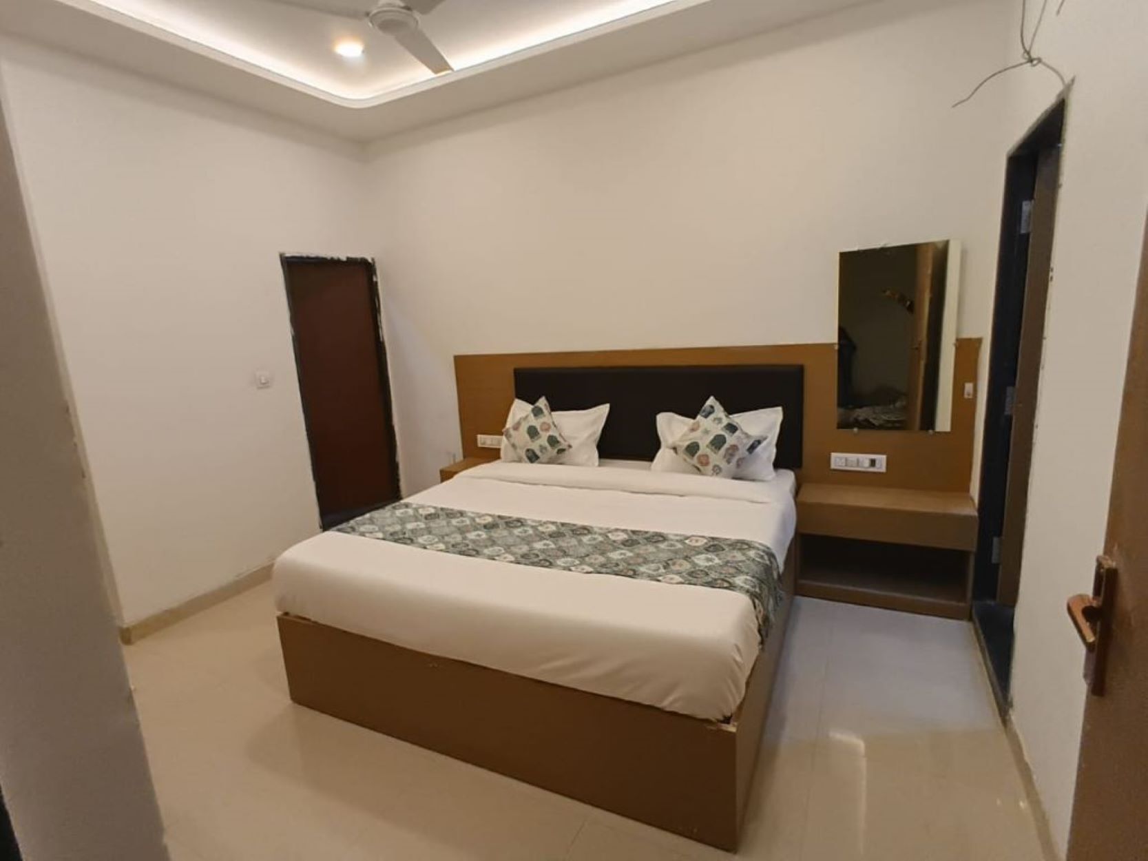 Une chambre à coucher moderne avec un lit, une table de chevet, un miroir et un ventilateur de plafond.