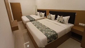 A hotel room with two beds, a ceiling fan, and a small bedside table. - Hotel JMM Mount View (Udaipur)