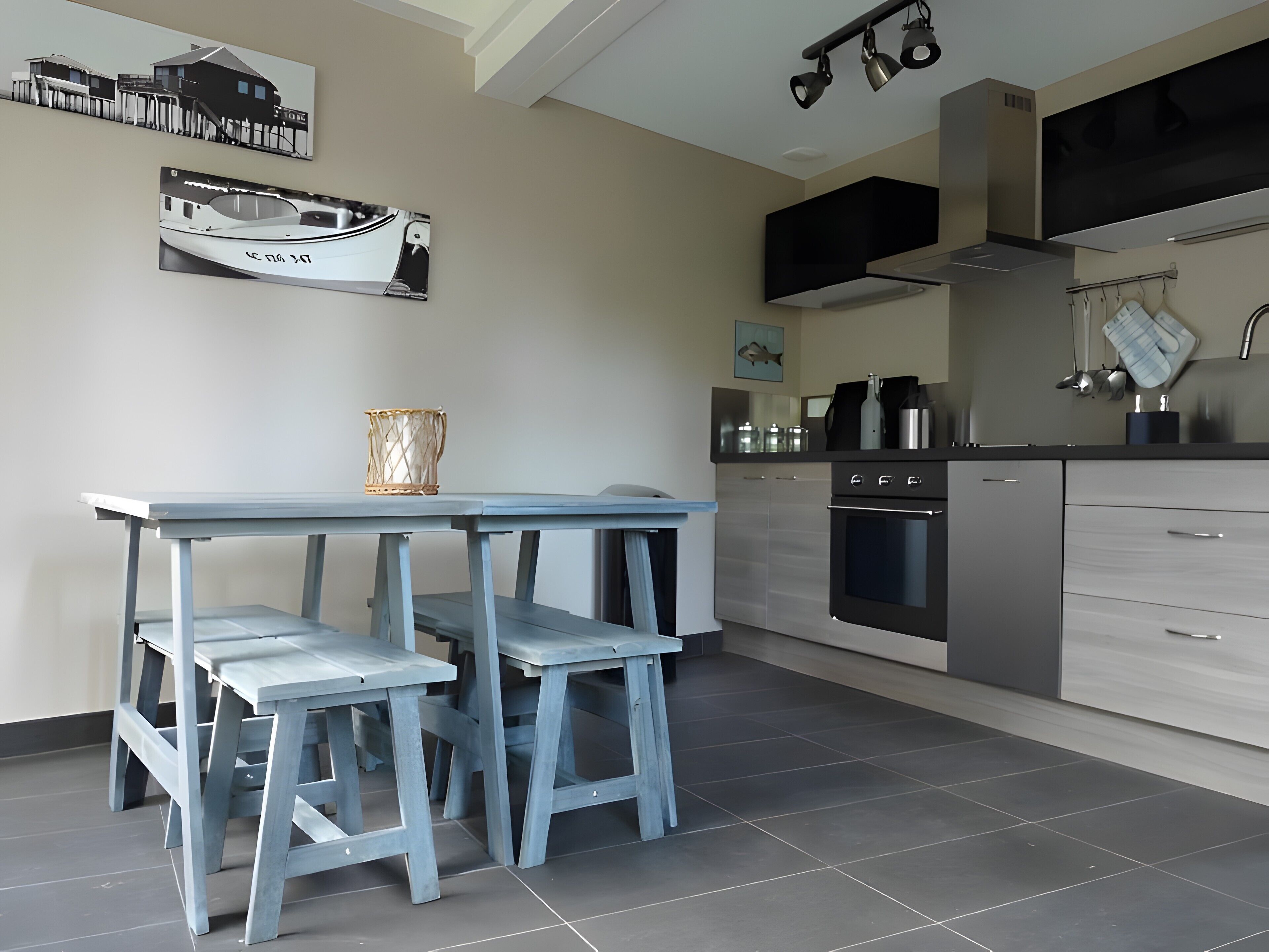 Een moderne keuken met een eethoek, met een tafel en krukken, een fornuis, oven en een spoelbak.
