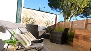 A patio with wicker furniture, a potted plant, and a wooden fence.