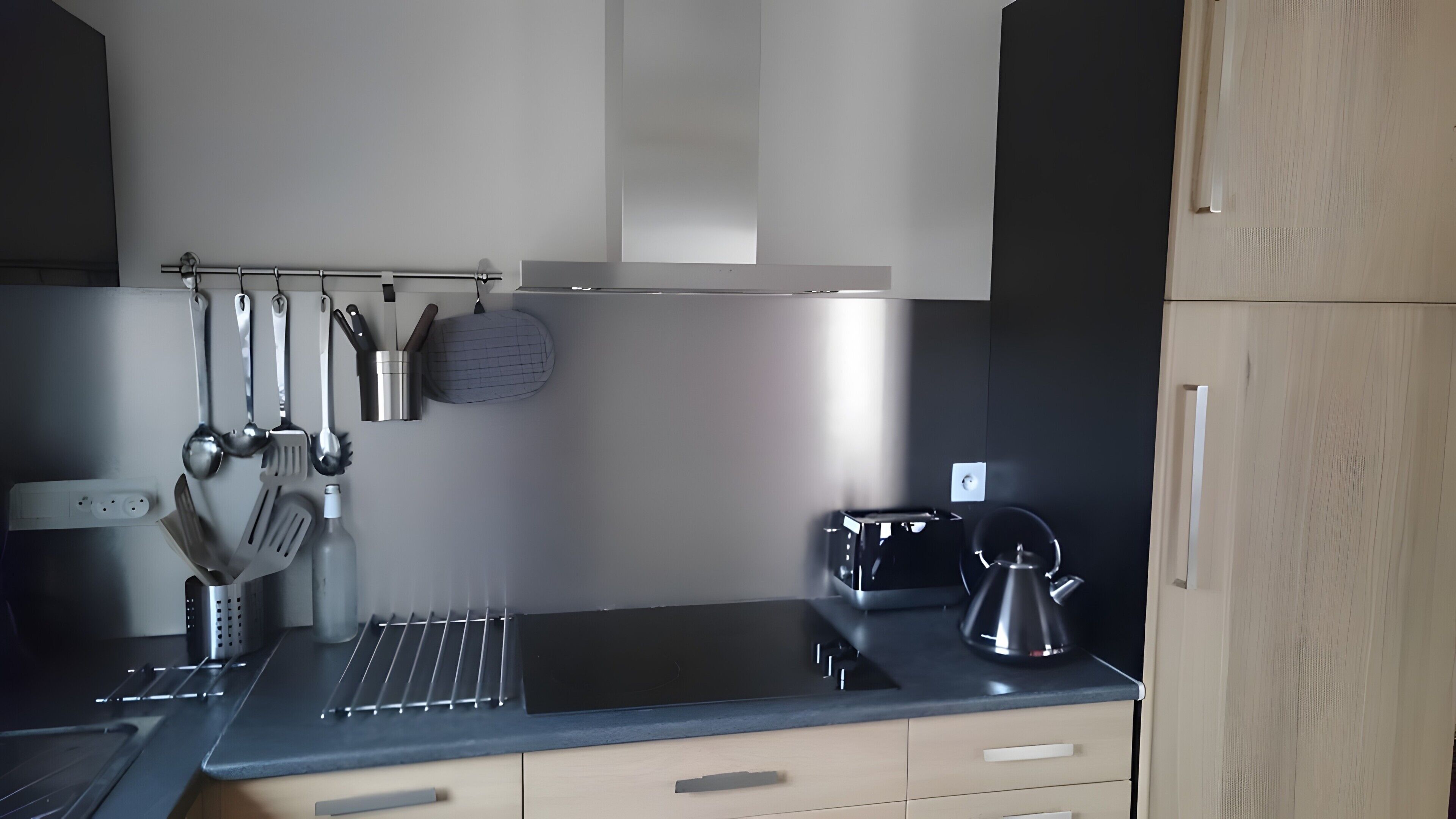 Eine moderne Küche mit schwarzem Arbeitsplatz, Edelstahlgeräten und einer hängenden Küchenutensilienstange.