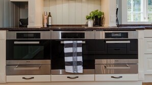 A modern kitchen with built-in appliances, a central island, and a window providing natural light.