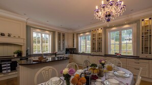 A spacious kitchen with white cabinetry, a large island, and a dining area set for a meal.