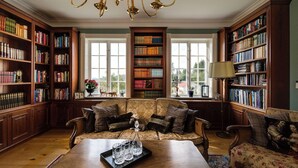 A library with bookshelves, a sofa, and a chandelier.