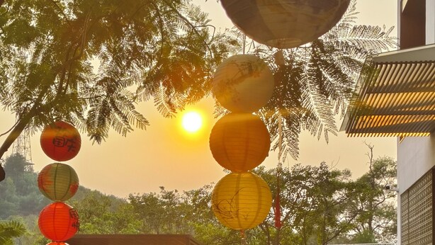 A courtyard with a modern building, a wooden fence, and traditional lanterns. - GuanLu Art hotel (Guangzhou)